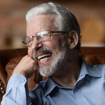 Man with dentures smiling from his couch