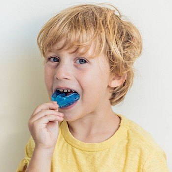 Little boy placing blue athletic mouthguard