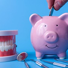 A piggy bank and dental instruments on a blue background