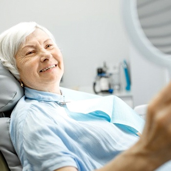 older woman admiring her smile in the mirror