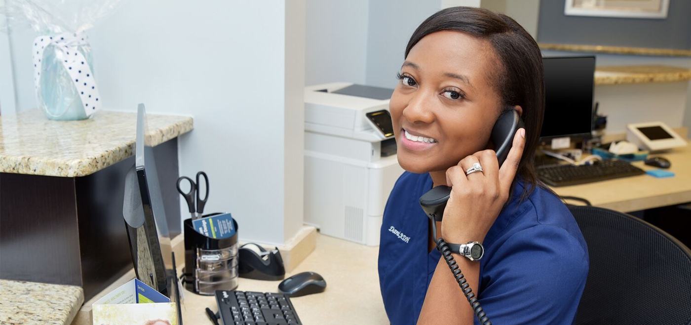 Smiling team member discussing dental insurance with patient on phone
