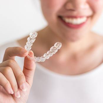 person holding an Invisalign aligner in their hand 