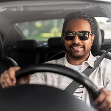 a smiling man driving home from the dentist’s office