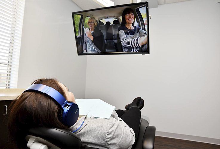 Relaxed dentistry patient watching TV in dental exam room