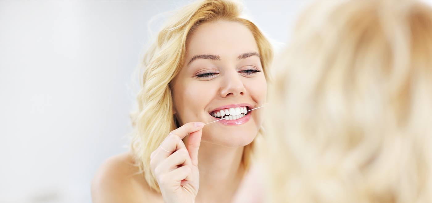 Woman flossing teeth to prevent gum disease