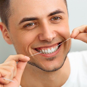 Man flossing teeth to prevent gum disease after antibiotic therapy