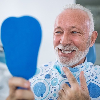 Older man looking at healthy smile thanks to periodontal maintenance